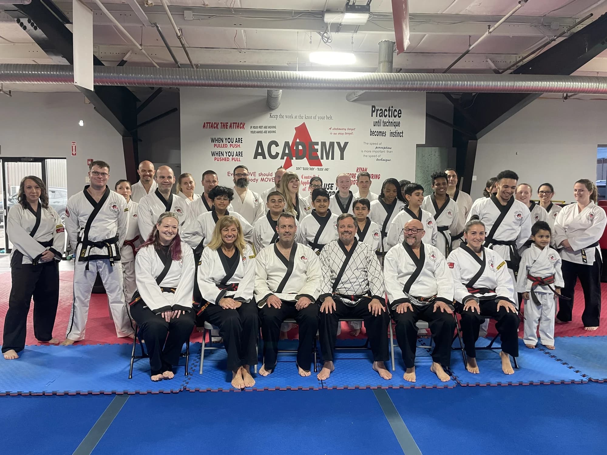 Grandmaster Waldron with Academy students and instructors beneath the Academy wall graphic