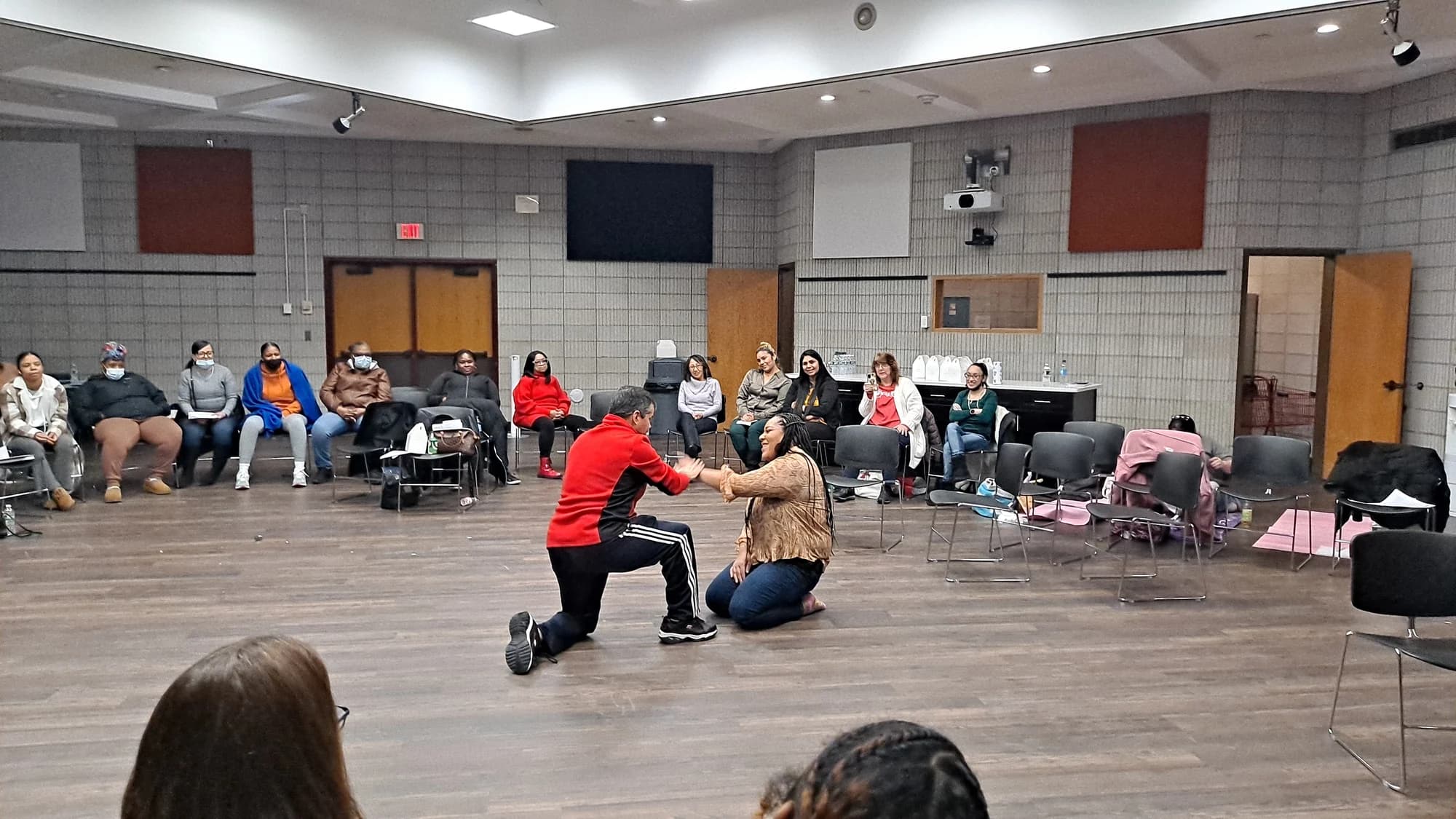 Community members learning a practical self-defense technique in an Academy workshop
